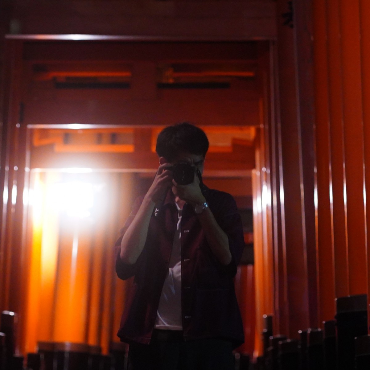 伏見稲荷の鳥居の中央でカメラを構えているしょへの写真。
