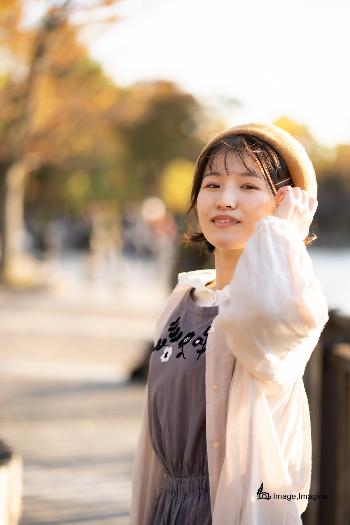 秋の大阪城で女性を撮影した写真。女性は左手で髪をかき分けながらこちらに目線を向けている。